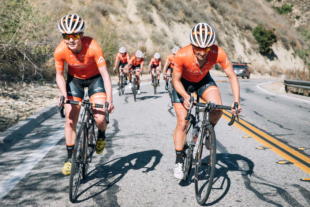 Megan Heath and Sara Bergen riding bikes together uphill